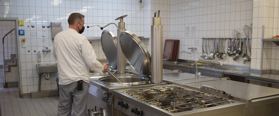 Ein Bediensteter der JVA Essen steht am Herd der Anstaltsküche