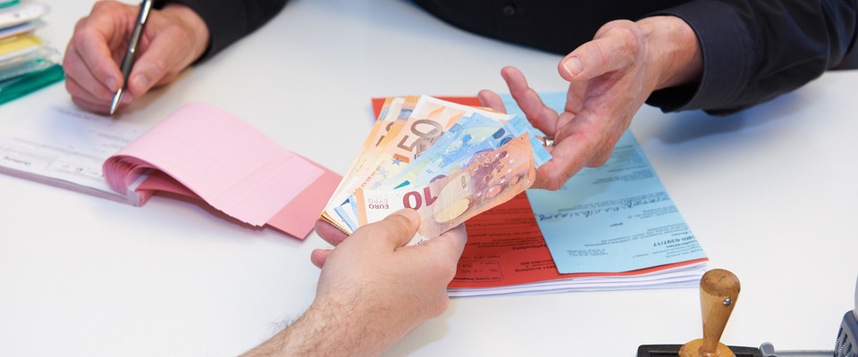 Eine Person übergibt Bargeld und erhält eine Quittung